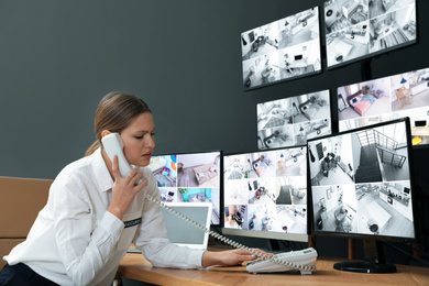 Photo of Sad security guard talking on telephone workplace indoors