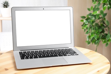 Photo of Modern laptop with blank screen on table indoors. Copy space text