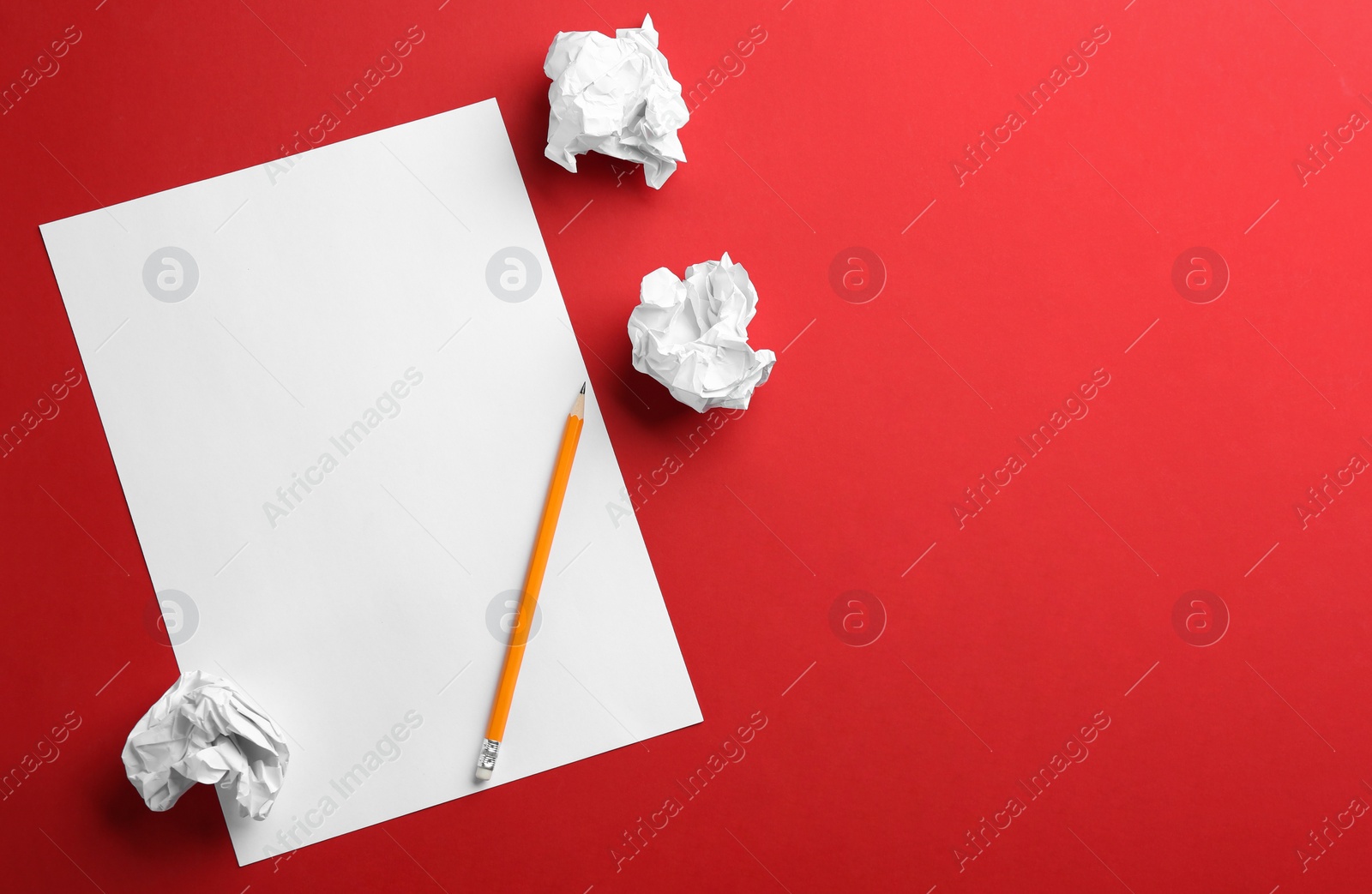 Photo of Blank sheet, pencil and crumpled paper balls on red background, flat lay. Space for text