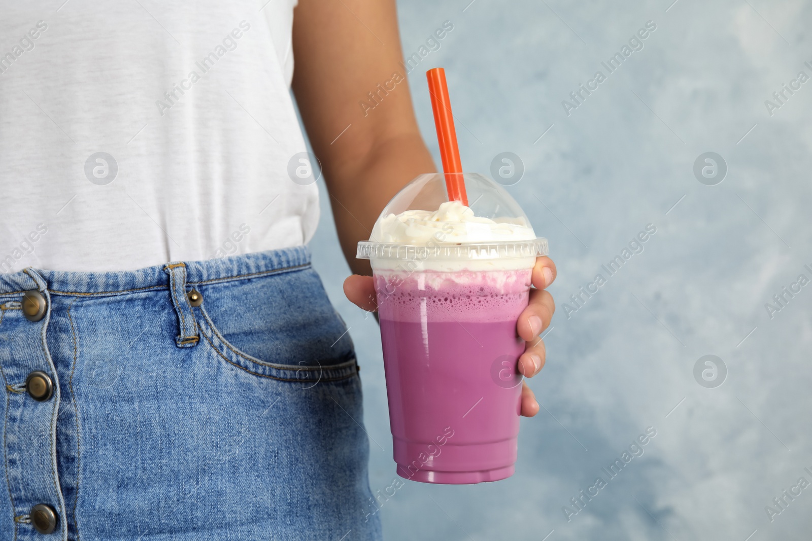 Photo of Woman with plastic cup of tasty milk shake on color background, closeup