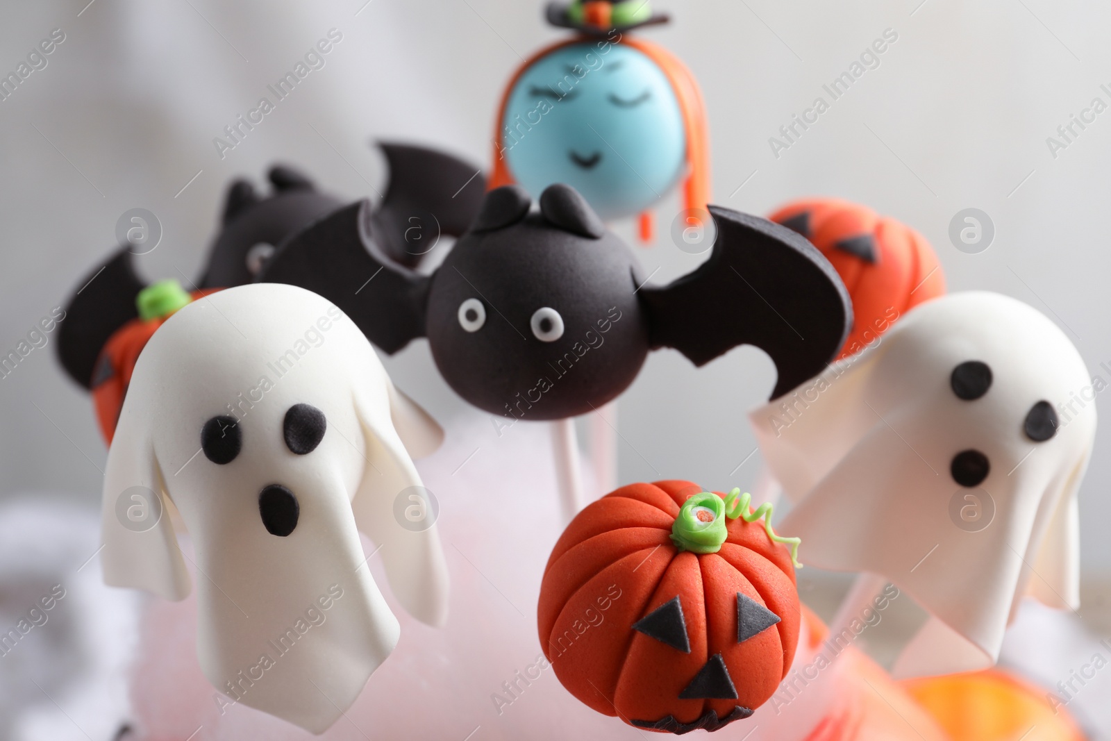 Photo of Different Halloween themed cake pops on light background, closeup