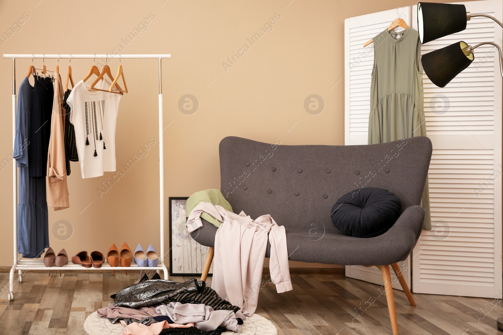 Photo of Messy dressing room with wardrobe rack and stylish armchair