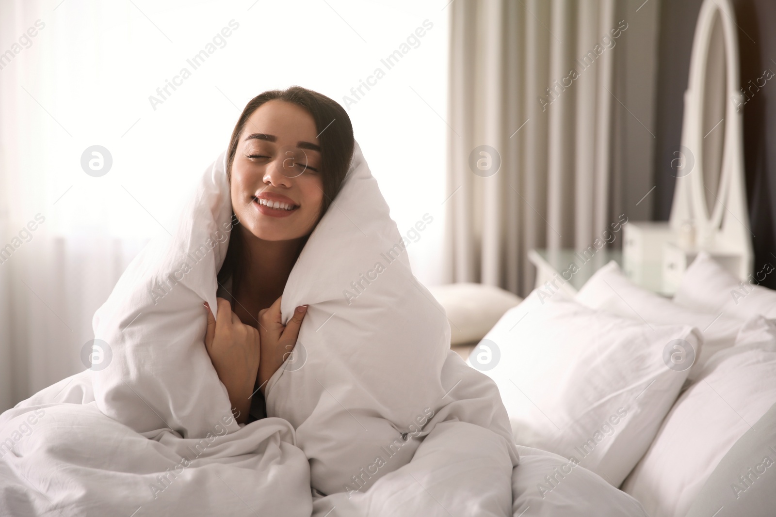 Photo of Beautiful young woman wrapped with soft blanket on bed at home