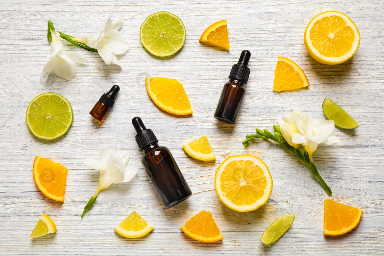 Photo of Flat lay composition with bottles of citrus essential oil on white wooden background