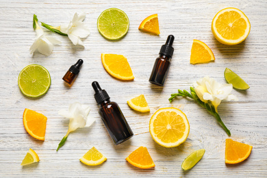 Photo of Flat lay composition with bottles of citrus essential oil on white wooden background