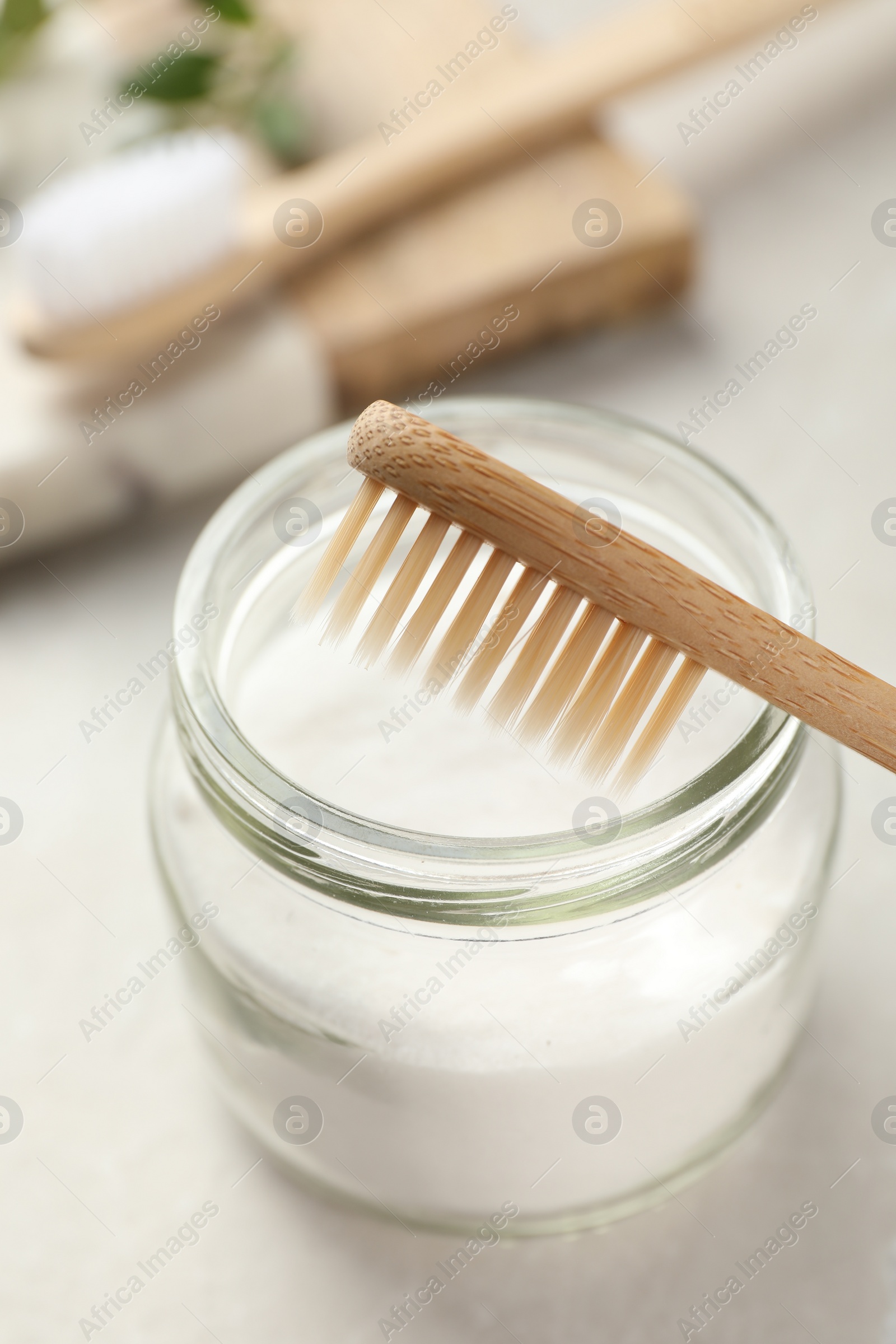 Photo of Bamboo toothbrush and jar of baking soda on table, closeup