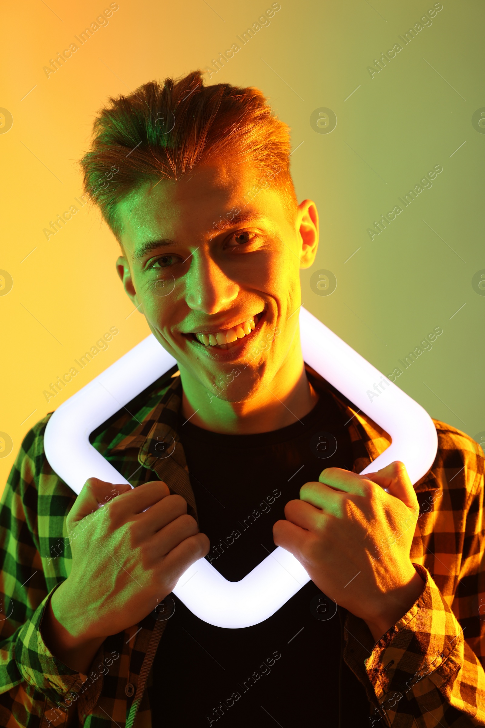 Photo of Young man with square lamp on color background in neon lights