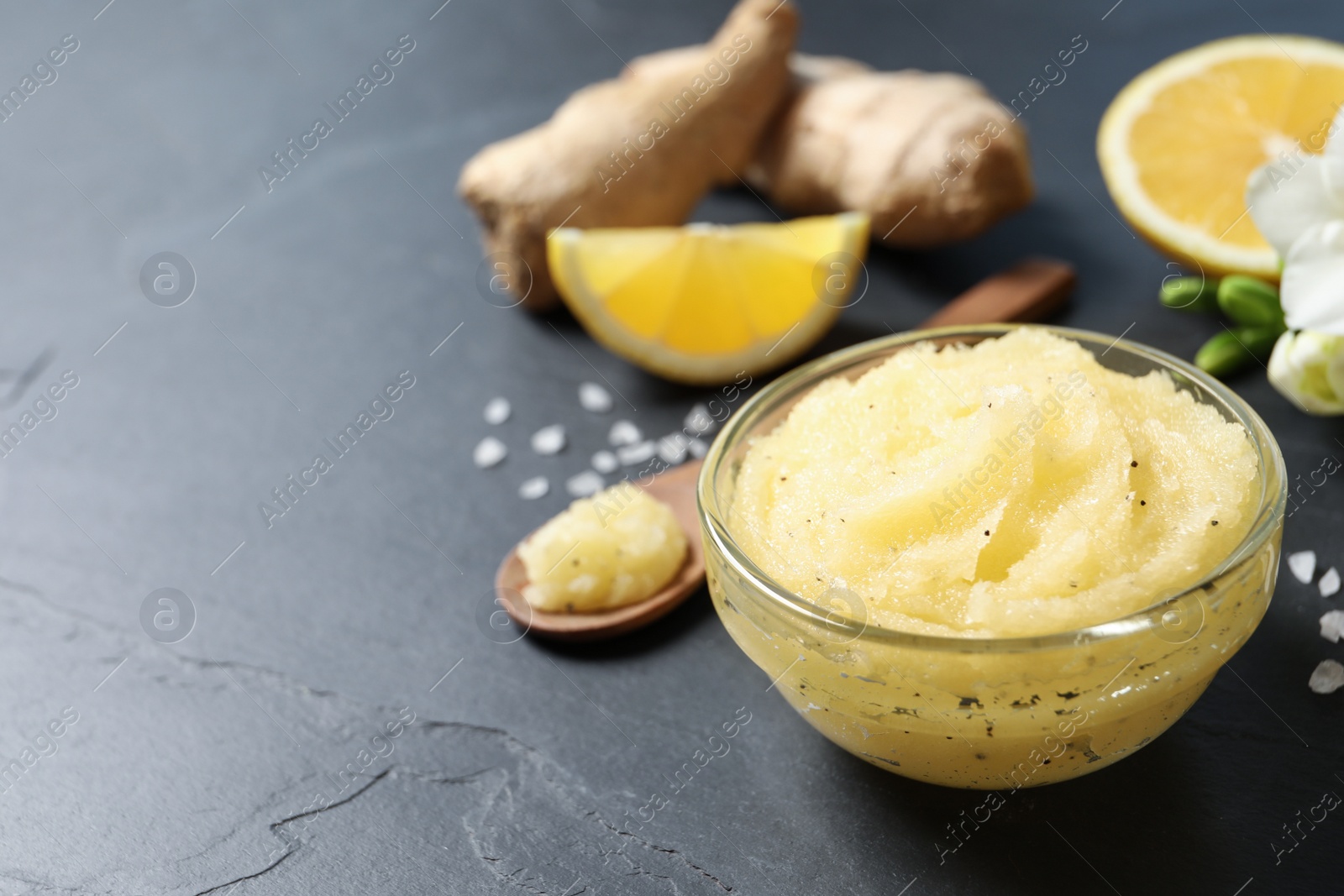 Photo of Body scrub in glass bowl on black table, space for text