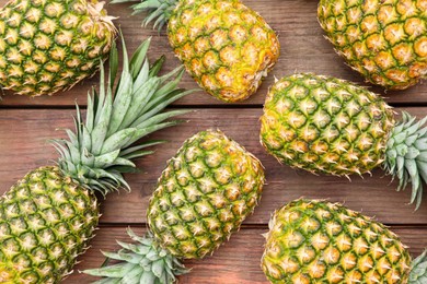 Delicious ripe pineapples on wooden table, flat lay