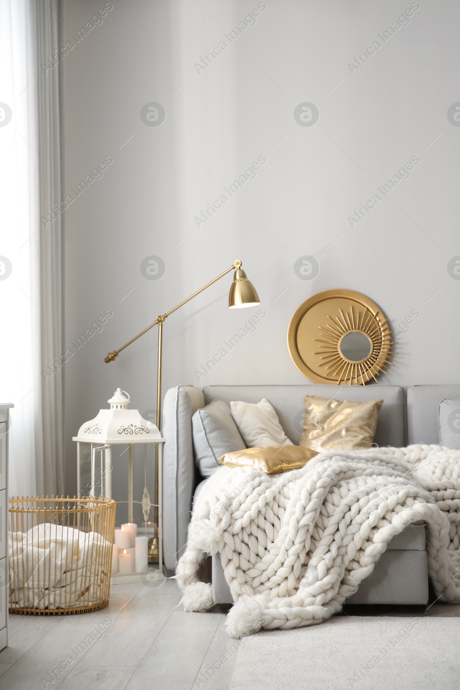 Photo of Cozy living room interior with knitted blanket on comfortable sofa