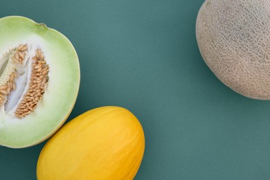 Photo of Different tasty ripe melons on teal background, flat lay. Space for text