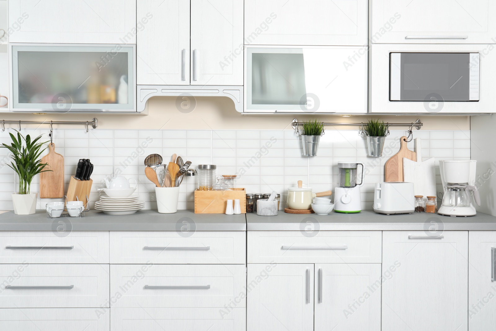 Photo of Different appliances, clean dishes and utensils on kitchen counter