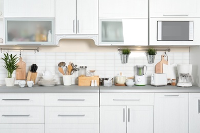 Photo of Different appliances, clean dishes and utensils on kitchen counter