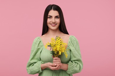 Photo of Happy young woman with beautiful bouquet on dusty pink background