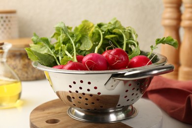 Photo of Wet radish in colander on white table, closeup