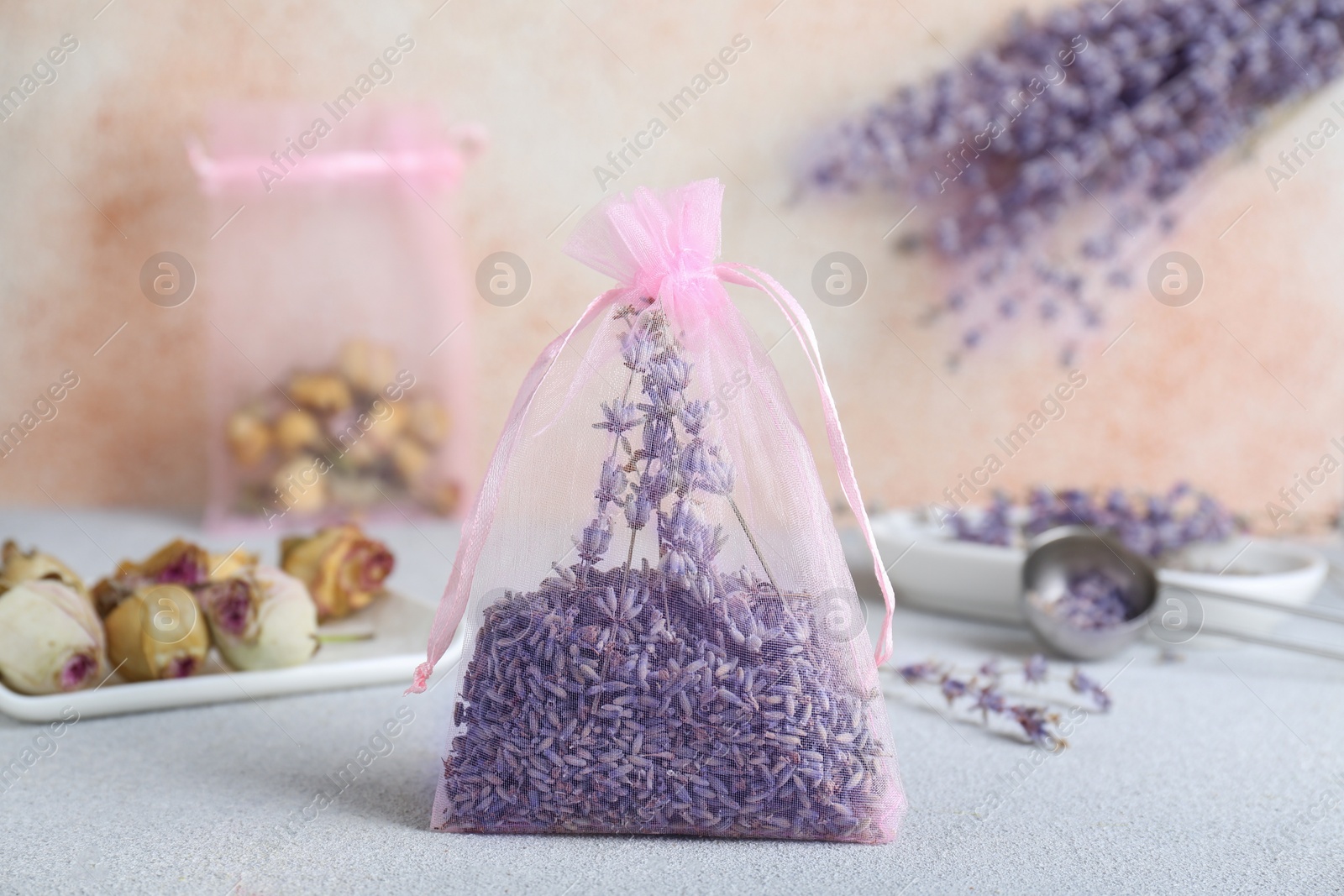 Photo of Scented sachet with dried lavender flowers on light gray table