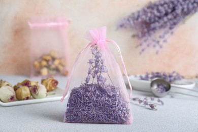 Scented sachet with dried lavender flowers on light gray table