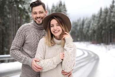 Cute couple outdoors on snowy day, space for text. Winter vacation