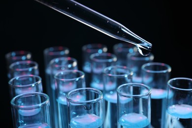 Photo of Dripping reagent into test tube on black background, closeup. Laboratory analysis