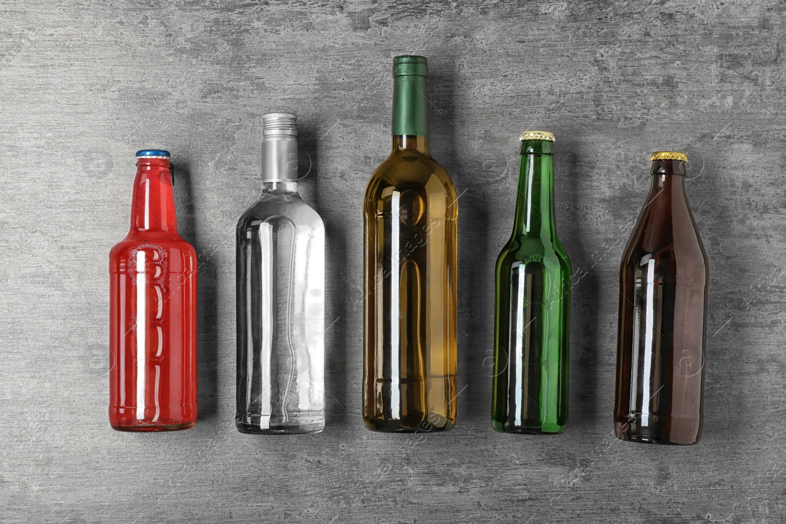 Photo of Bottles with different alcoholic drinks on grey background, top view