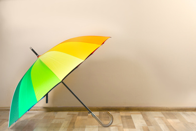 Beautiful open colorful umbrella near beige wall. Space for text