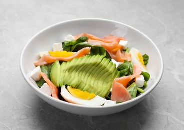 Photo of Delicious salad with boiled egg, salmon and avocado on light grey marble table, closeup