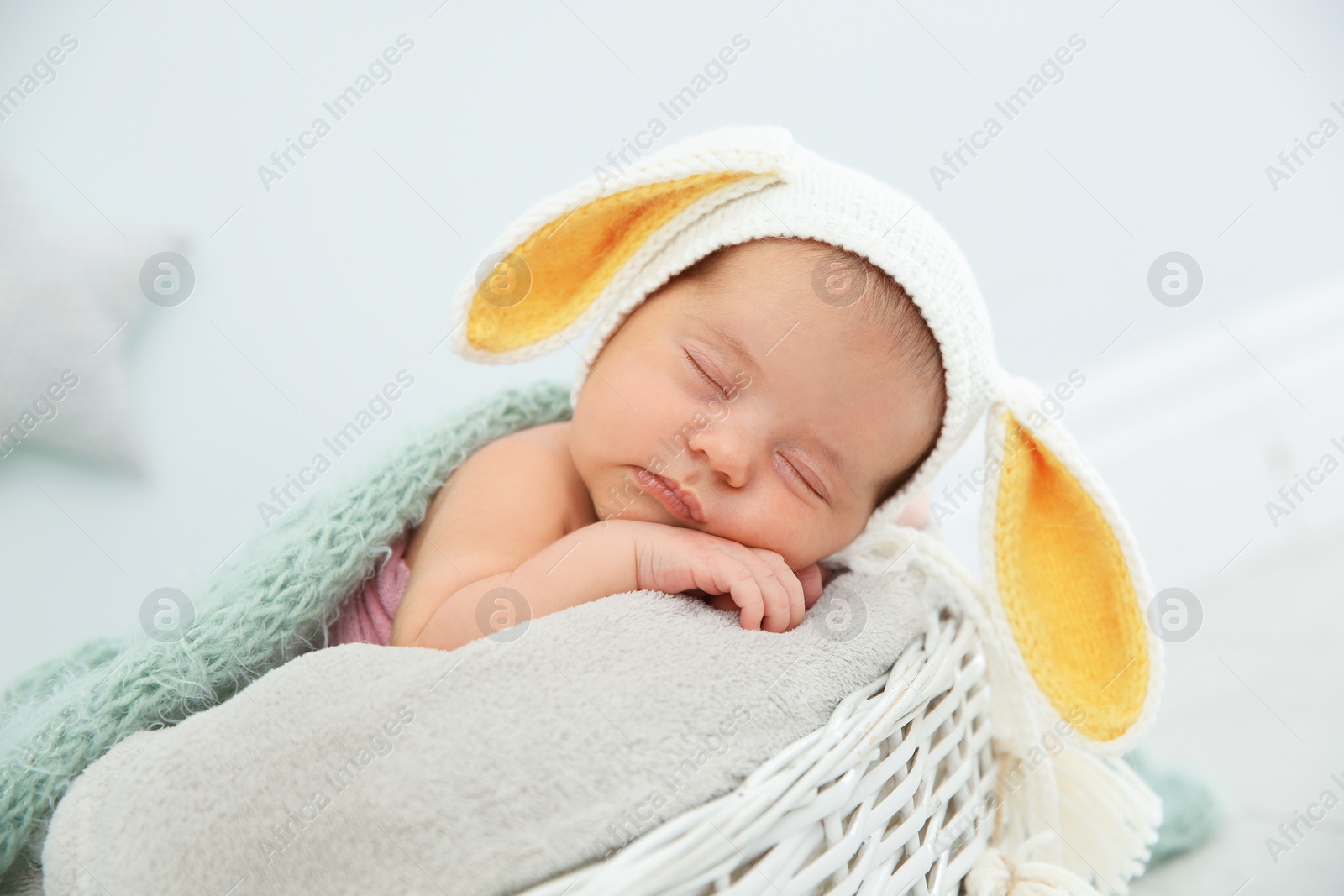 Photo of Adorable newborn child wearing bunny ears hat in baby nest indoors