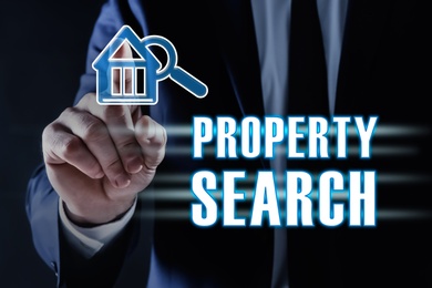 Property search concept. Man using virtual screen with house and magnifier icon, closeup