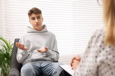 Psychologist working with teenage boy in office