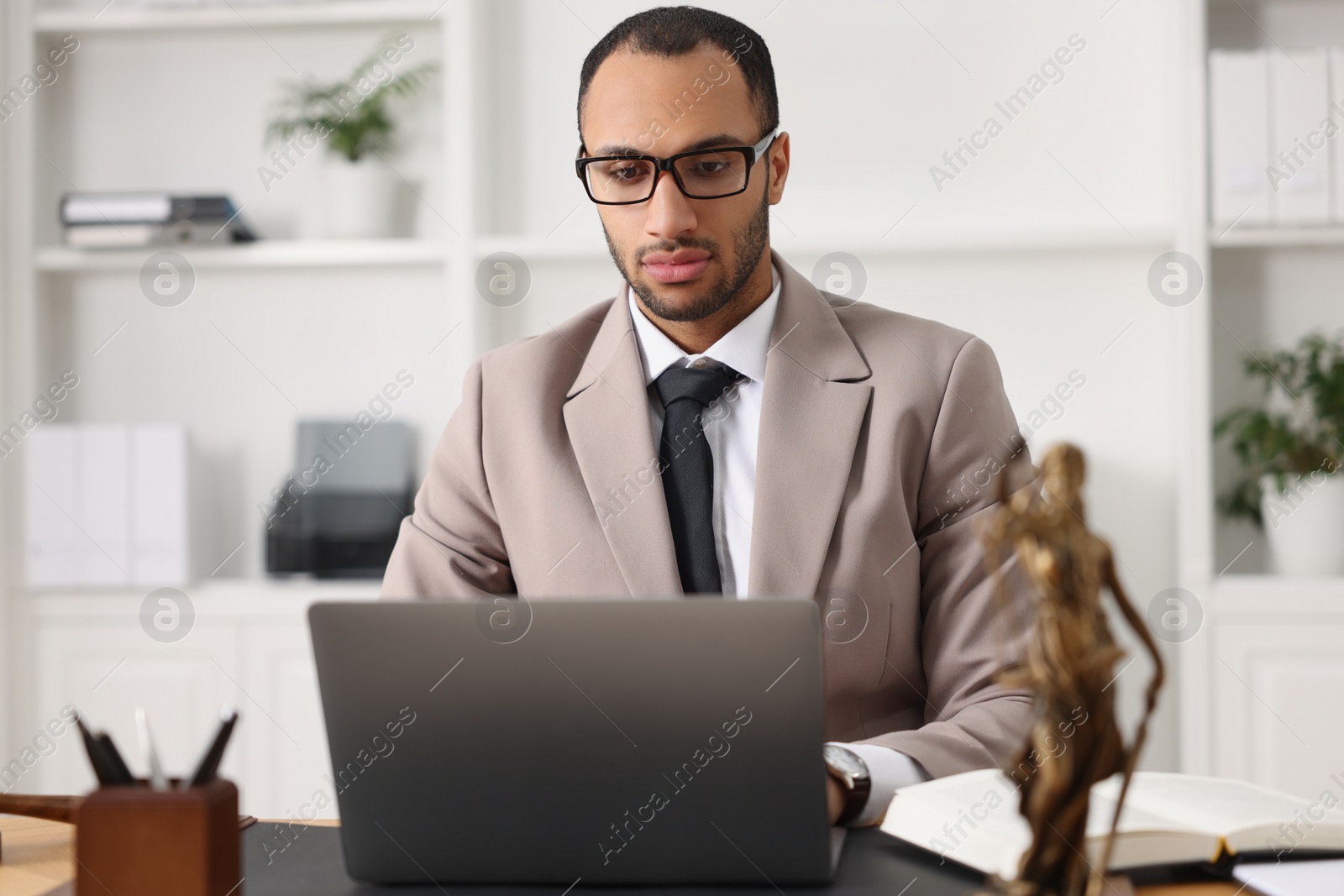 Photo of Serious lawyer working with laptop at table in office