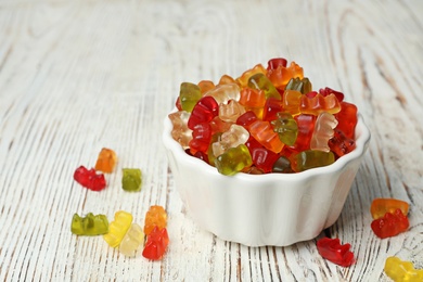 Photo of Bowl with delicious jelly bears on wooden table. Space for text