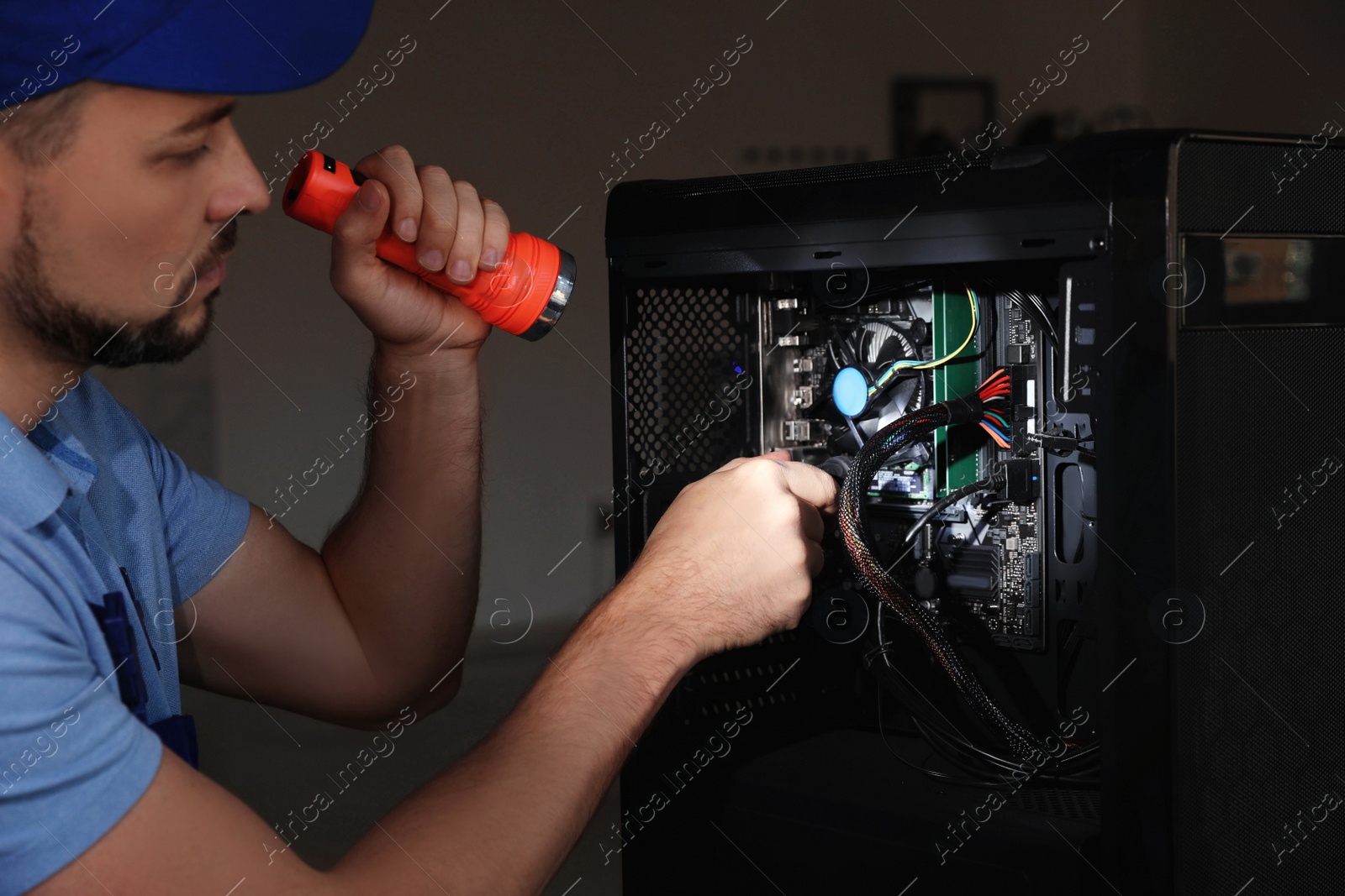 Photo of Repairman with flashlight fixing system unit indoors, closeup