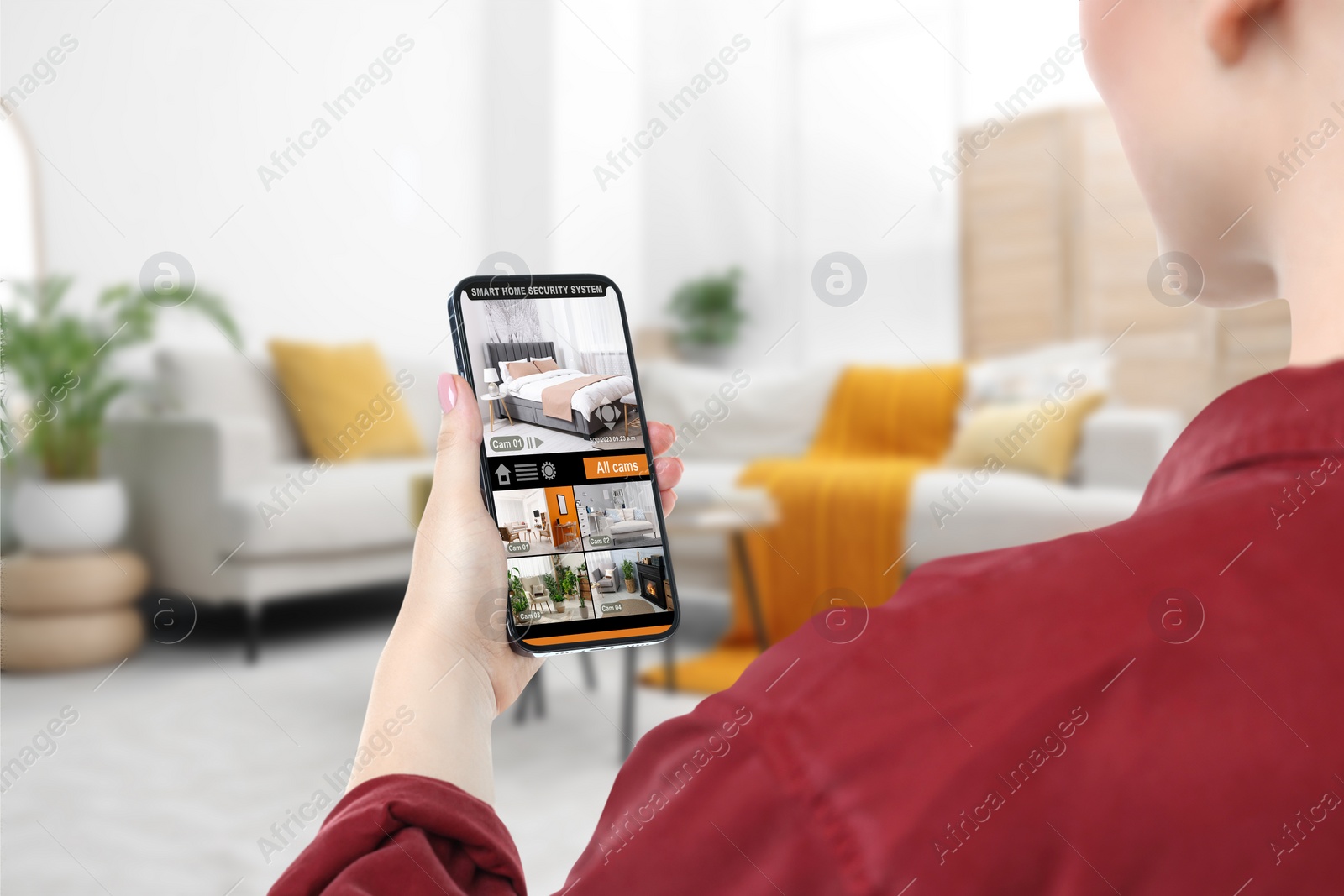 Image of Woman using smart home security system on mobile phone indoors, closeup. Device showing different rooms through cameras