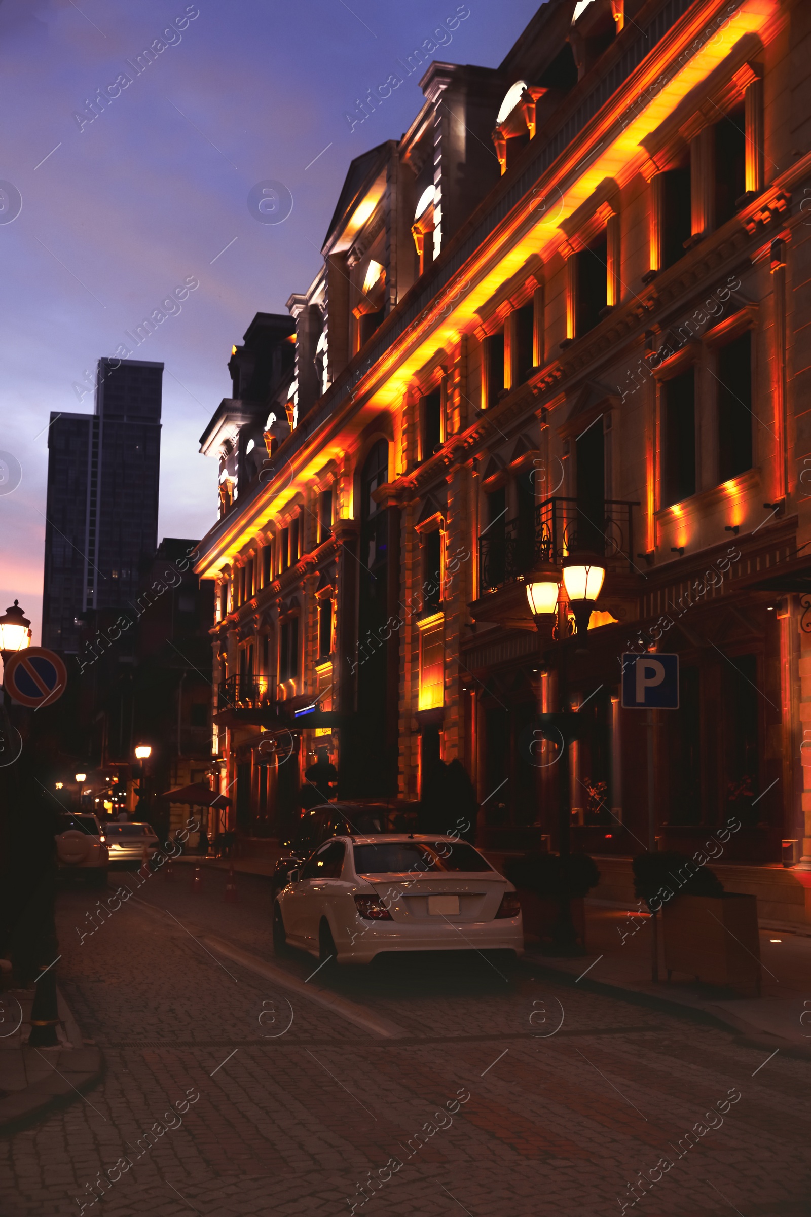 Photo of Beautiful cityscape with glowing streetlights, cars and illuminated building in evening