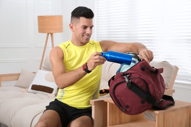 Photo of Man packing sports stuff for training into bag at home