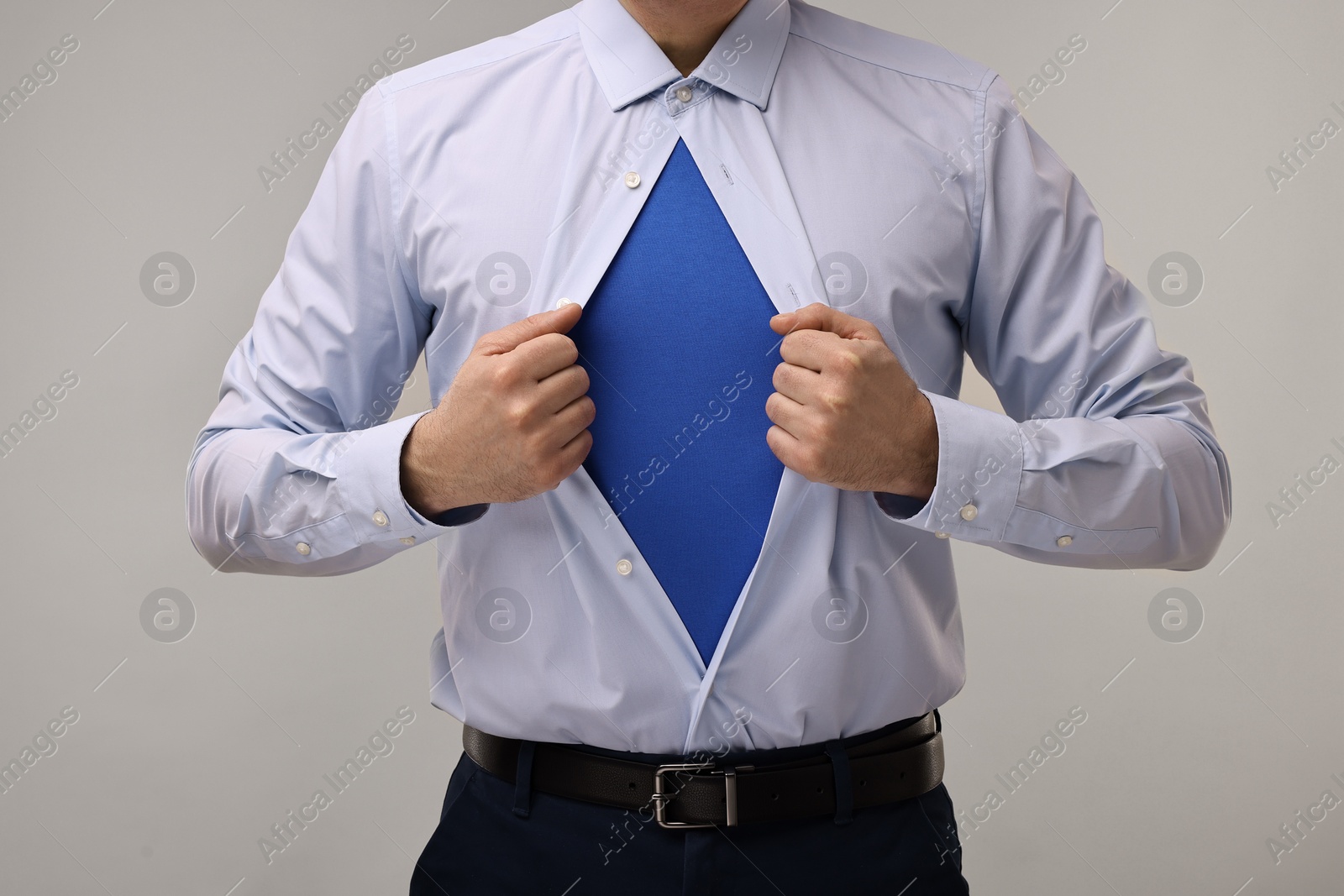 Photo of Businessman wearing superhero costume under suit on beige background, closeup