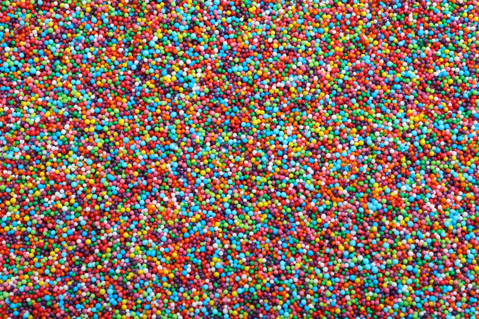 Photo of Bright colorful sprinkles as background, top view. Confectionery decor