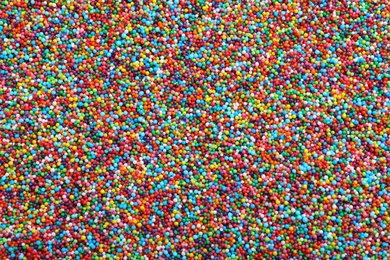 Bright colorful sprinkles as background, top view. Confectionery decor