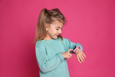 Little girl with smart watch on pink background