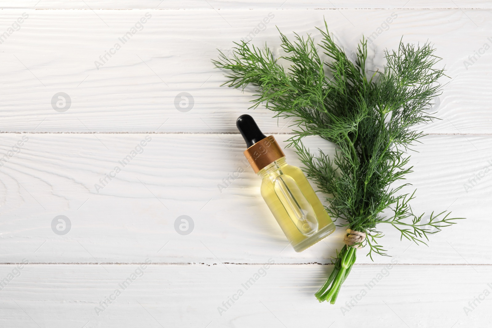 Photo of Bottle of essential oil and fresh dill on white wooden table, flat lay. Space for text