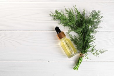 Bottle of essential oil and fresh dill on white wooden table, flat lay. Space for text