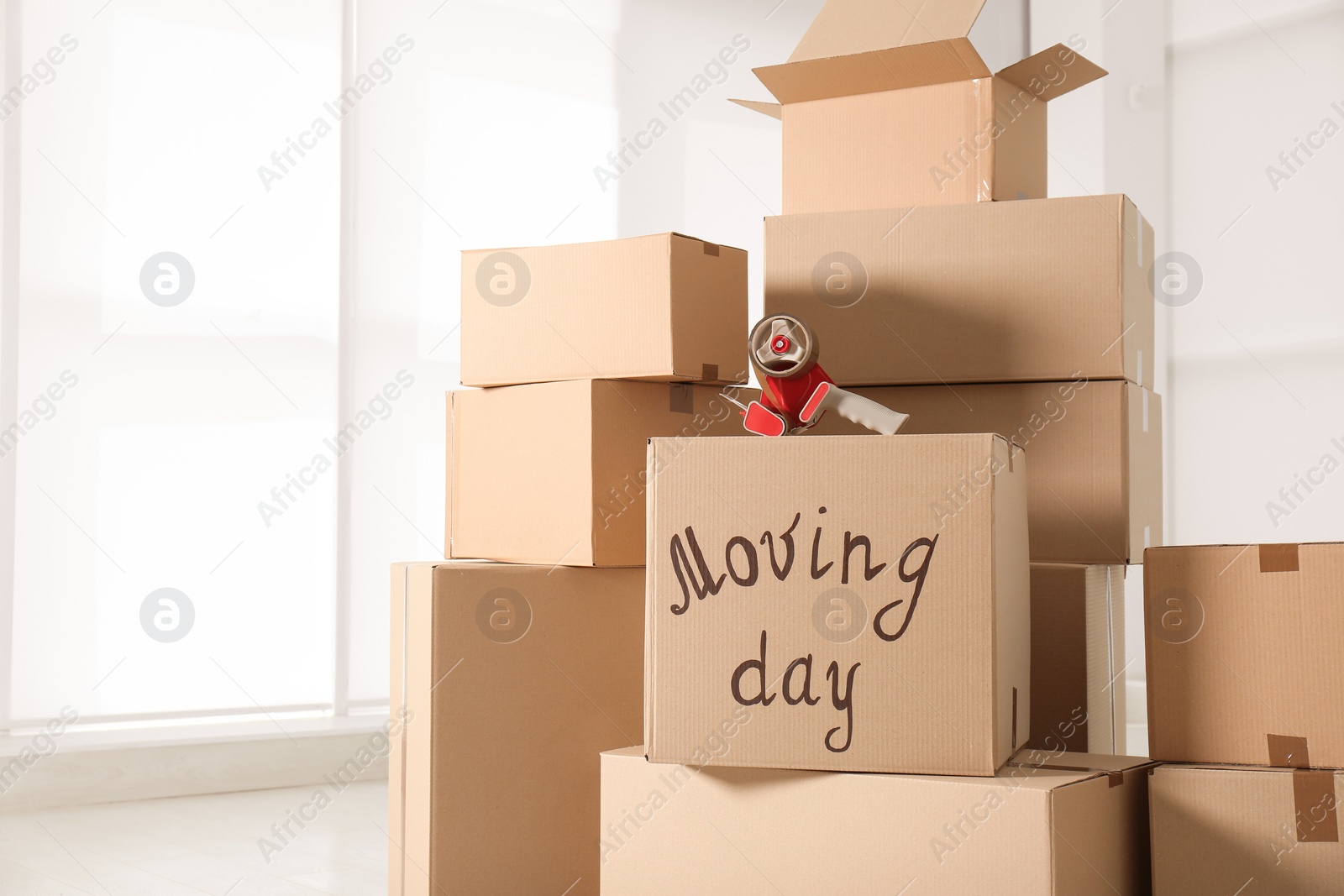 Photo of Pile of moving boxes and adhesive tape indoors, closeup