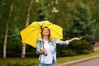 Photo of Happy young woman with umbrella under rain in park