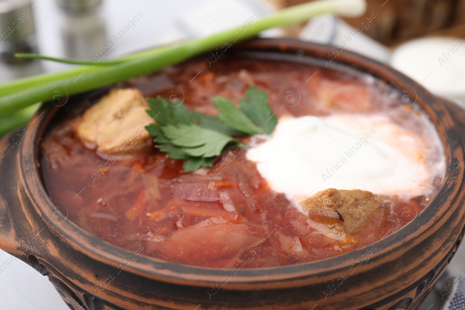 Photo of Tasty borscht with sour cream in bowl on table, closeup