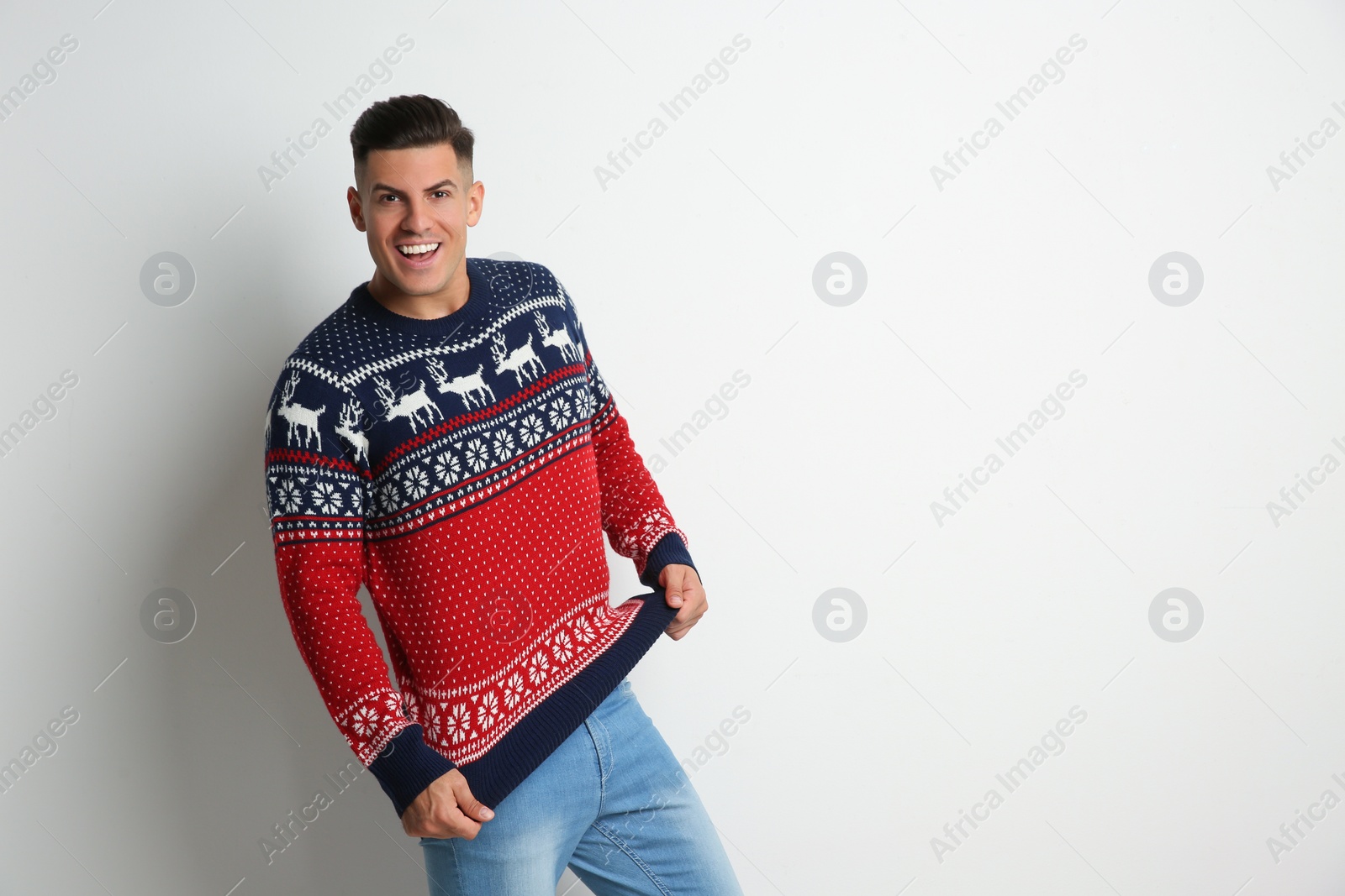 Photo of Happy man showing his Christmas sweater on white background, space for text