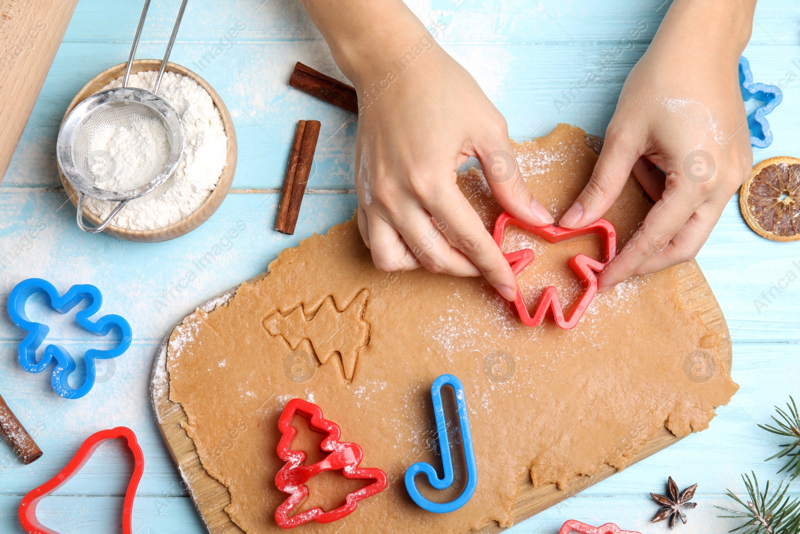 Photo of Woman making Christmas cookies at light blue wooden table, top view