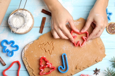 Photo of Woman making Christmas cookies at light blue wooden table, top view