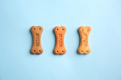Photo of Bone shaped dog cookies on light blue background, flat lay
