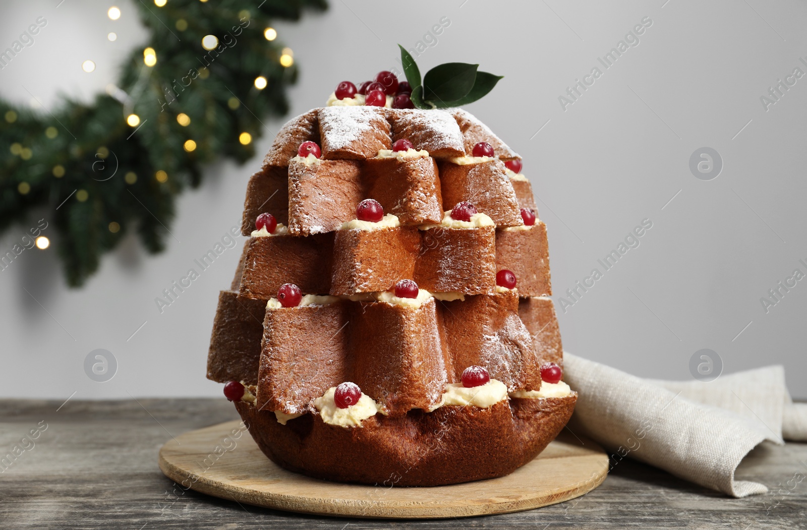Photo of Delicious Pandoro Christmas tree cake with powdered sugar and berries near festive decor on wooden table