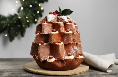 Photo of Delicious Pandoro Christmas tree cake with powdered sugar and berries near festive decor on wooden table
